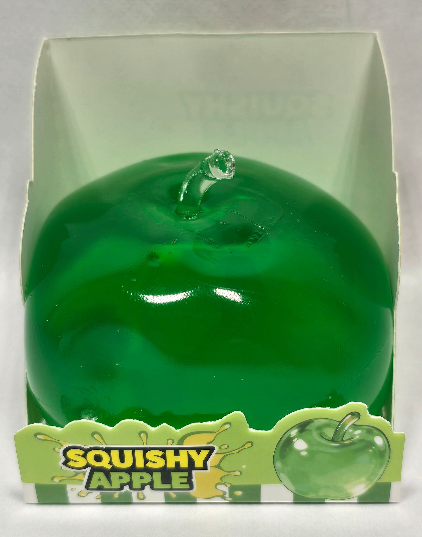 A green squishy apple toy in its clear plastic packaging with a green and yellow 'Squishy Apple' label, set against a plain light background.