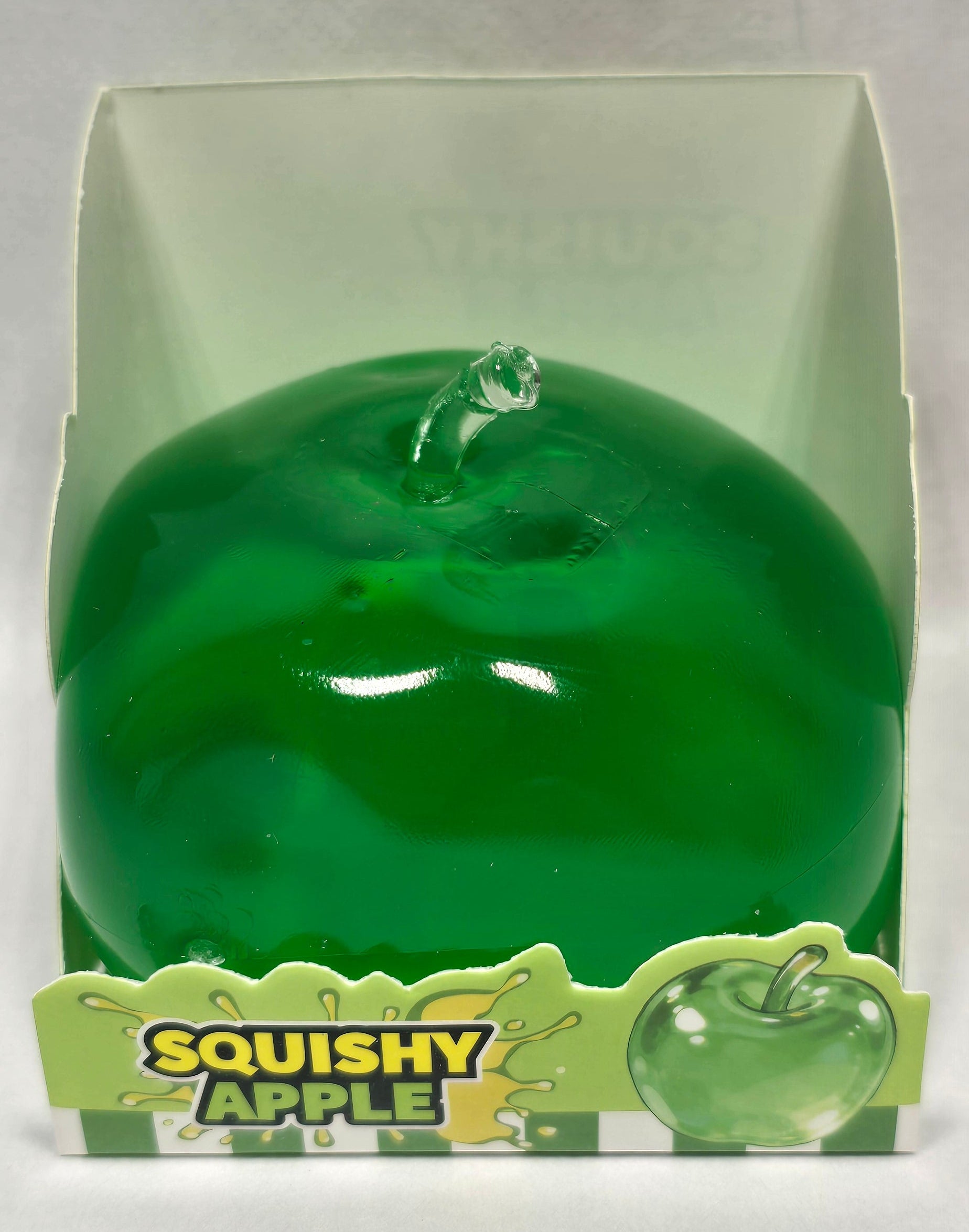A green squishy apple toy in its clear plastic packaging with a green and yellow 'Squishy Apple' label, set against a plain light background.