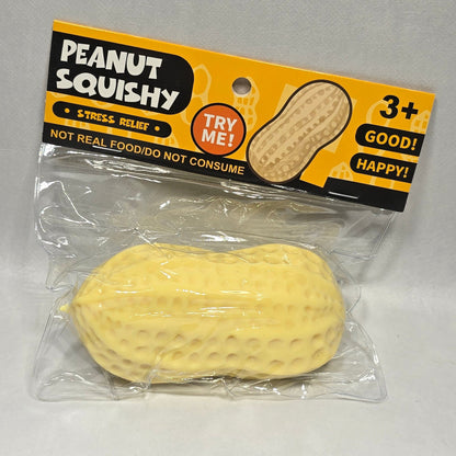 A packaged yellow peanut-shaped squishy toy with a black and yellow 'Peanut Squishy' retail card, photographed on a light gray surface.