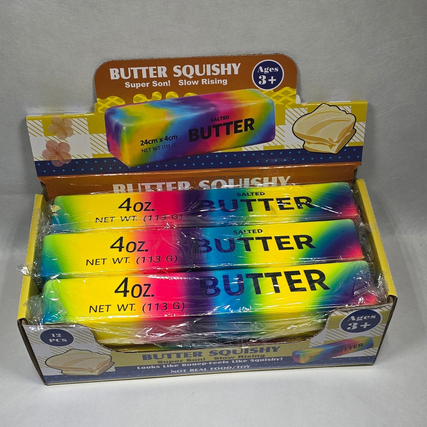 A box of 4 oz butter sticks with a colorful rainbow design, shown on a light gray surface.