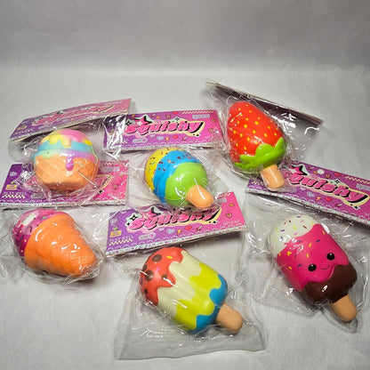 Six small novelty squishy toys shaped like fruit and desserts, each in its own clear plastic packaging with a pink backing card, arranged on a light gray surface.