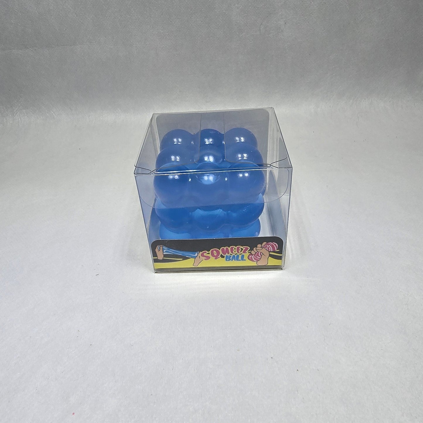 A small blue plastic toy or accessory inside a clear plastic sleeve, placed on a light gray textured surface.