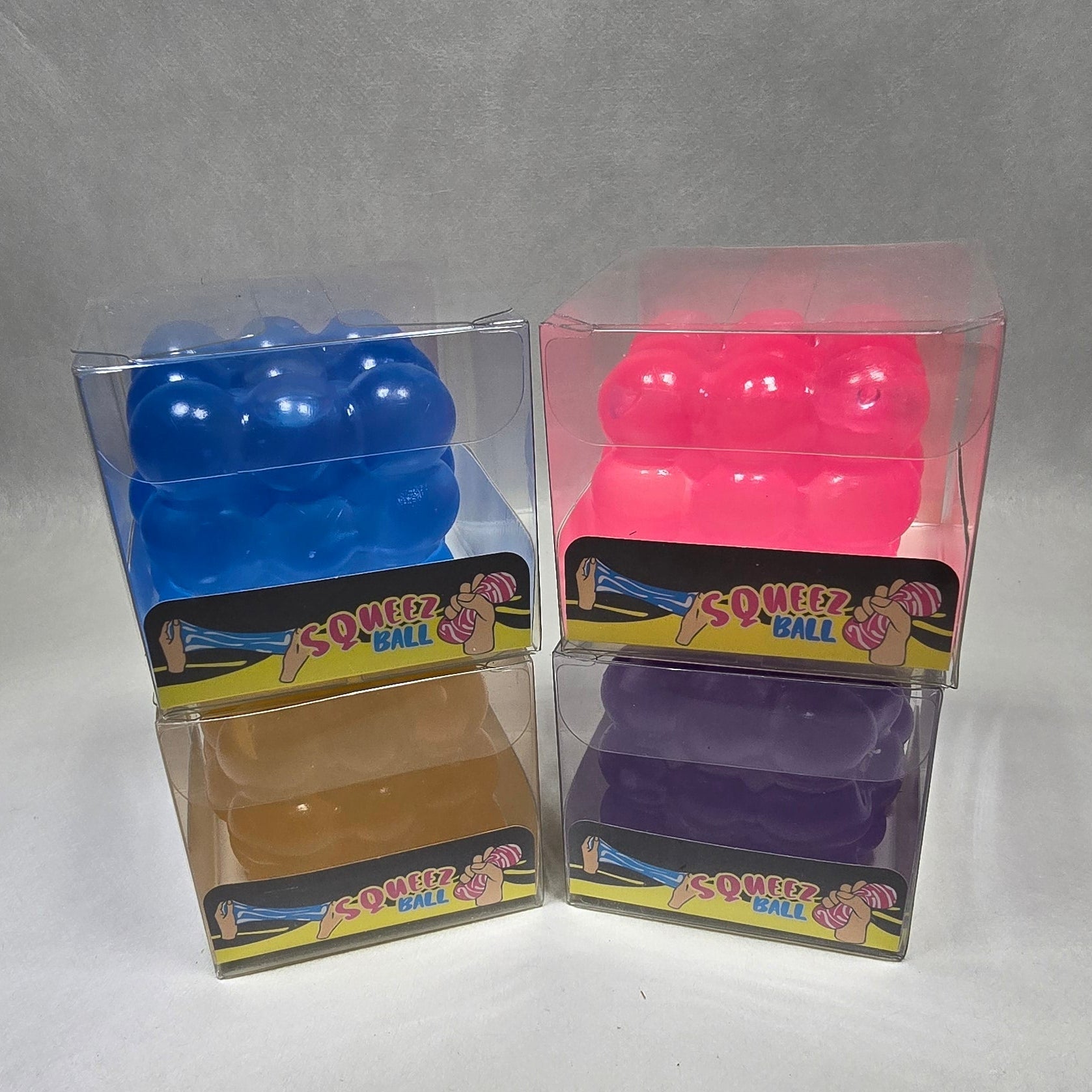 Three small packaged novelty items arranged in a 2x3 grid on a light gray surface. The packages contain brightly colored plastic pieces, including pink, purple, blue, and tan, with colorful labels that appear to read 'Hot Wheels' and 'Magic'.