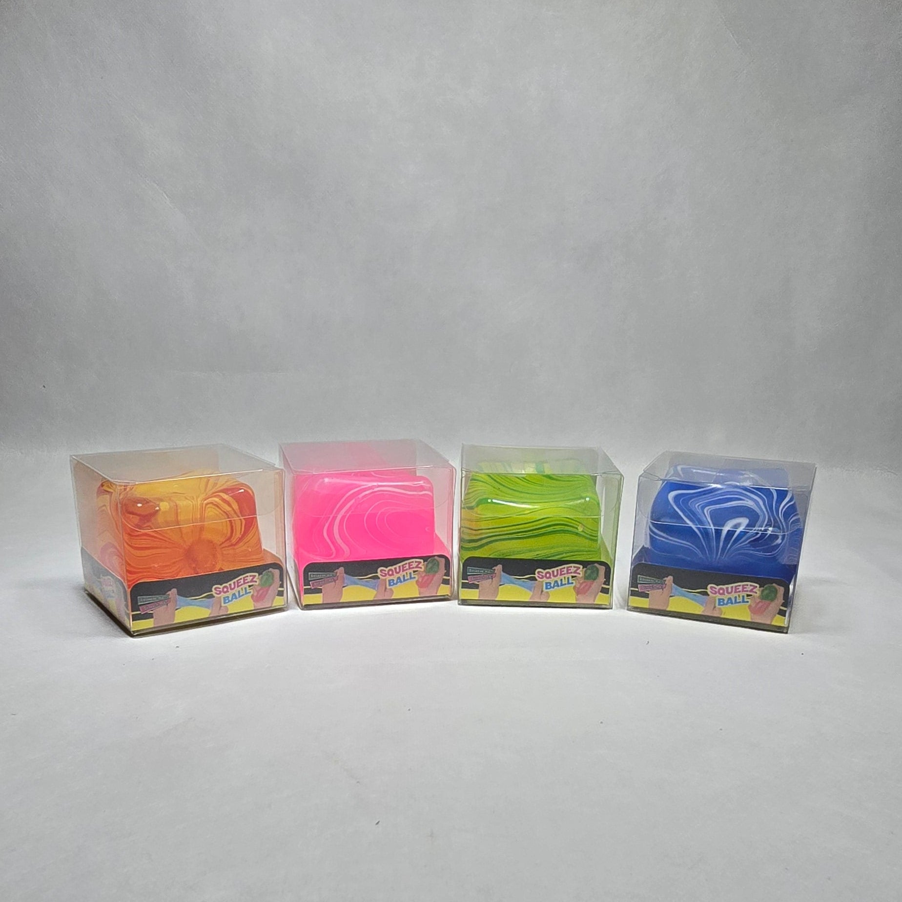 Four small rectangular packages of colorful material arranged vertically on a light gray textured surface. The packages contain blue, green, pink, and orange materials, with one showing a visible 'PVC' label.